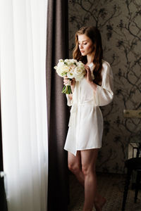 Young woman standing against white wall