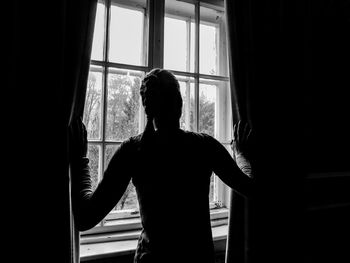 Rear view of woman looking through window