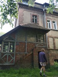 Rear view of woman standing by building