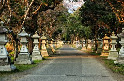 Empty footpath amidst stone lanterns at park