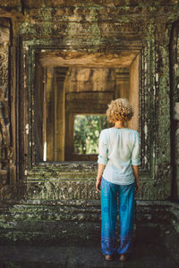 Rear view of young woman standing at angkor wat