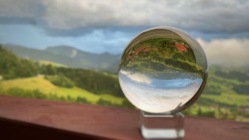 Close-up of glass on mountain against sky