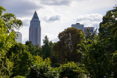 Trees and buildings against cloudy sky