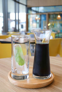 Carafe of iced butterfly pea flower tea served with a glass of mint-leaf iced cube
