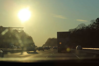 Cars on road in city against sky at sunset