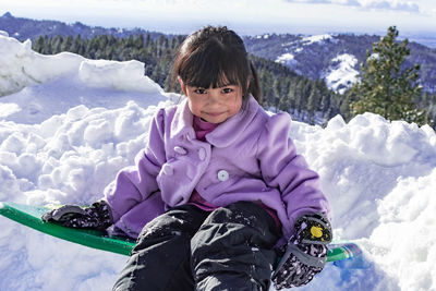 Portrait of smiling girl sitting on snow