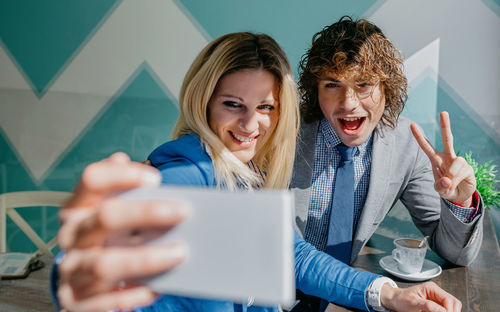 Businesswoman with colleague taking selfie from mobile phone at cafe