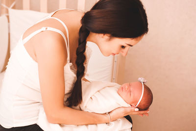 Young woman looking at her daughter at home