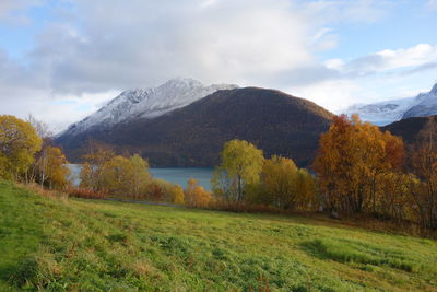 Scenic view of fjord and mountains against cloudy sky 