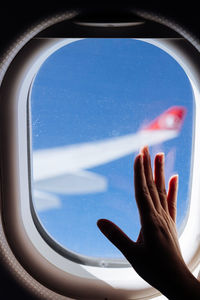 Cropped hand touching airplane window