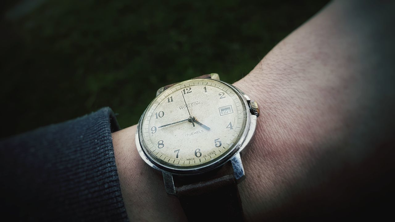 CLOSE-UP OF HUMAN HAND HOLDING CLOCK