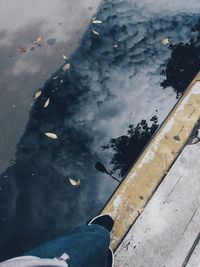 Low section of person on shore against sky