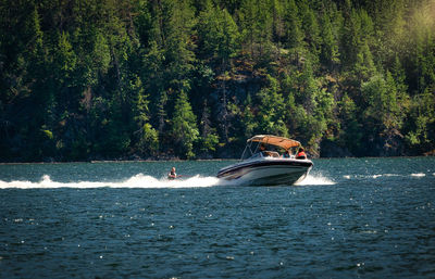 People riding boat on river against trees