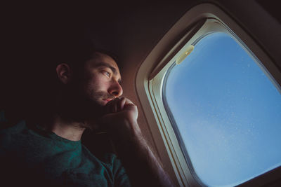 Portrait of young man looking through airplane window