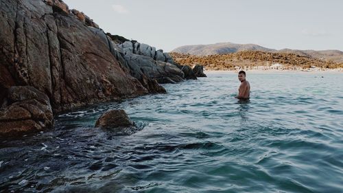Side view of shirtless man swimming in sea