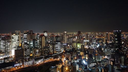 Illuminated modern buildings in city against sky at night