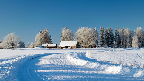 Snow covered field against clear blue sky