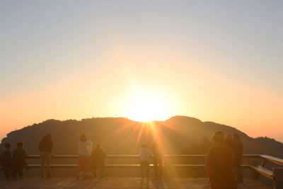 Silhouette people on mountain against sky during sunset