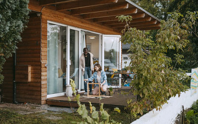 Man and woman helping each other while painting furniture on porch