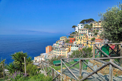 Scenic view of sea by buildings against clear blue sky