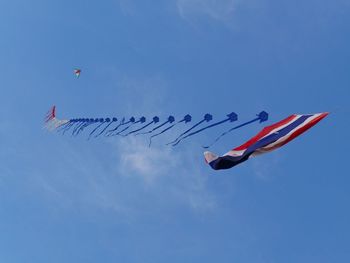 Low angle view of kite with flag flying against blue sky