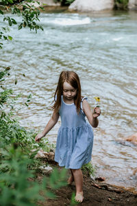 Young girl picking a flower near a river