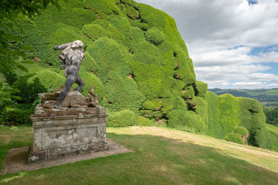 Statue amidst plants against sky