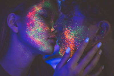 Close-up of couple with multi colored face paint kissing