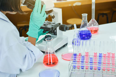 Female scientist using microscope at table in laboratory