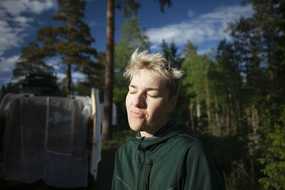 Woman with closed eyes relaxing in forest