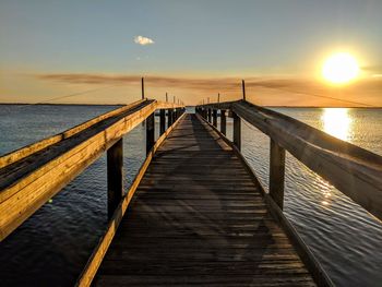 Pier over sea against sky during sunset