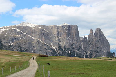 Grassy landscape with mountain in background against cloudy sky