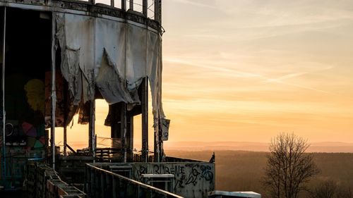 Abandoned building against sky during sunset