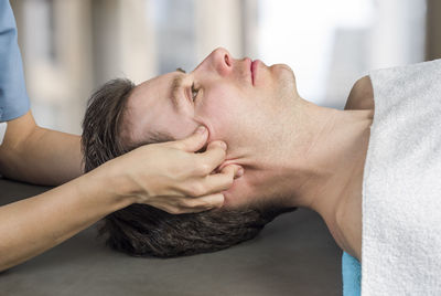 Cropped image of masseur massaging man in spa