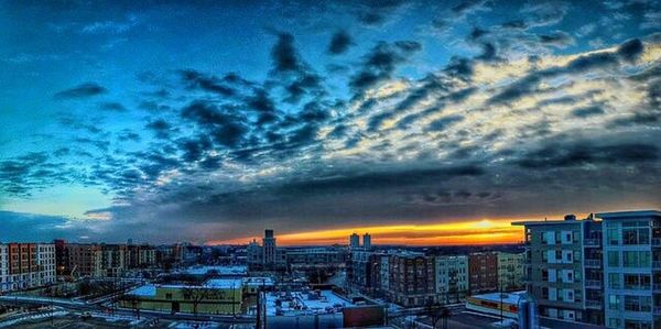 Cityscape against cloudy sky at sunset