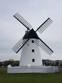 Traditional windmill on field against sky