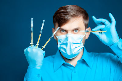 Portrait of doctor wearing mask holding syringes