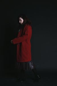 Young woman standing against black background