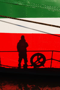 Silhouette people standing by railing against red wall