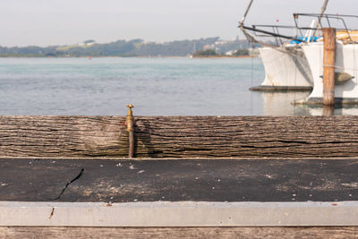 Sailboats moored on pier by sea against sky