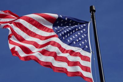 Low angle view of flag against clear blue sky