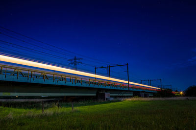 Train on railroad tracks against clear sky at night