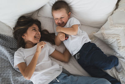 High angle view of happy sibling lying on bed at home