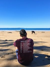 Rear view of man on beach against clear sky