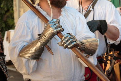 Midsection of man holding sword outdoors