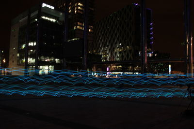 Light trails on street against buildings at night