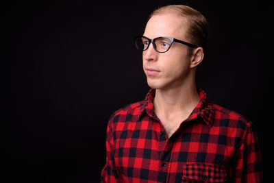 Portrait of young man wearing eyeglasses against black background