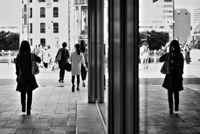 Men standing in front of people walking on footpath in city