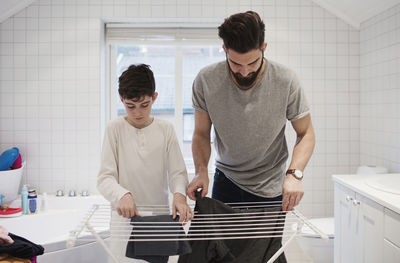 Father and son drying clothes on rack at home