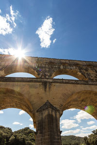 Low angle view of arch bridge against sky on sunny day